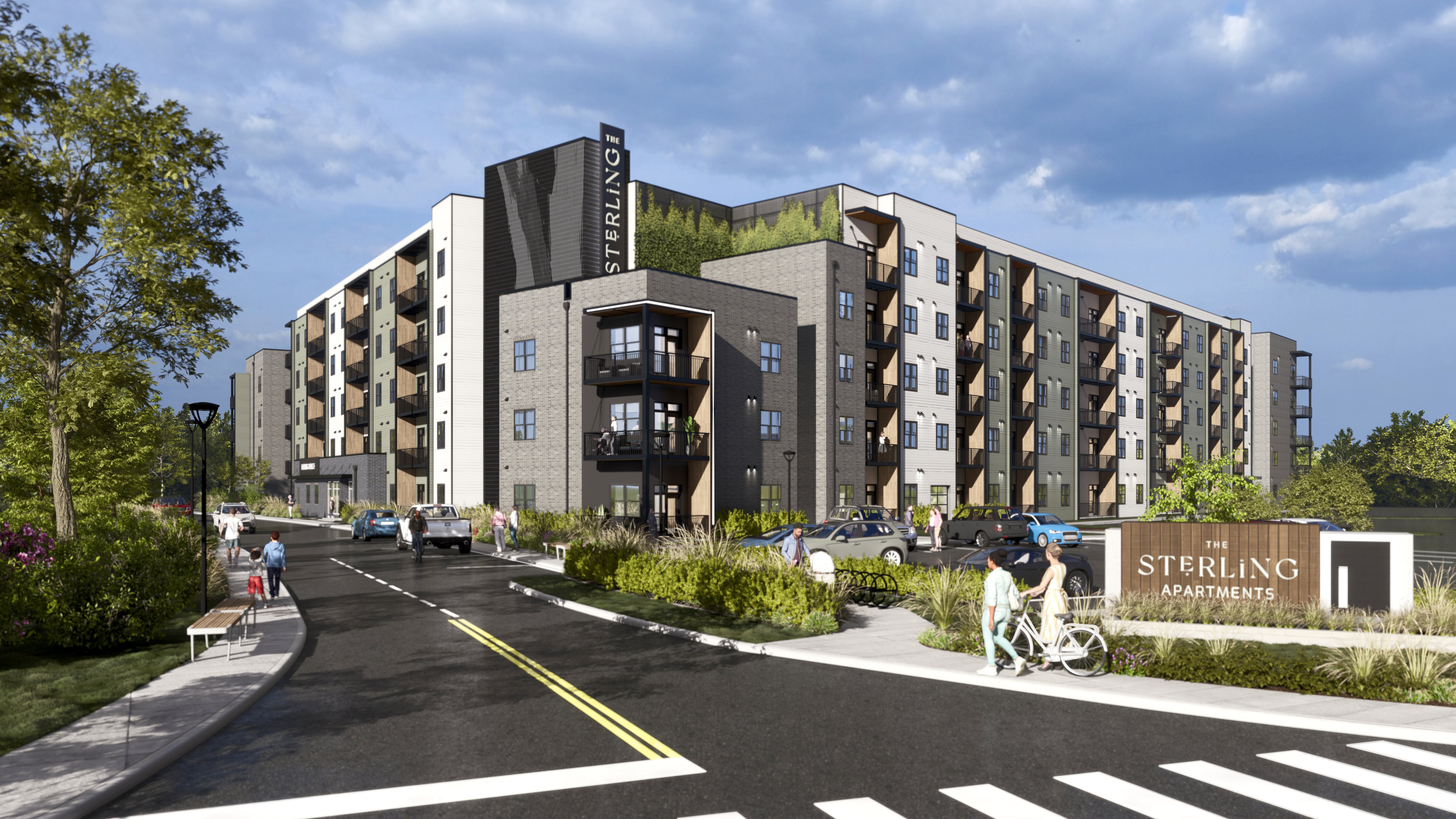 A Sterling apartment complex is shown with a person riding a bicycle on the street in front.